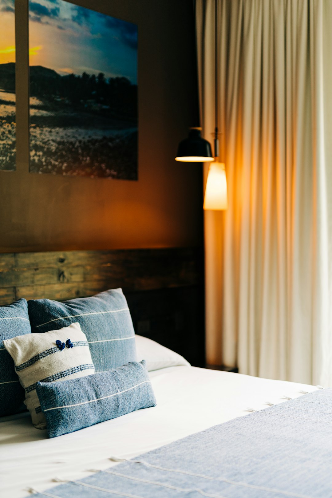 Hotelkamer met bed, blauwe kussens en schilderij