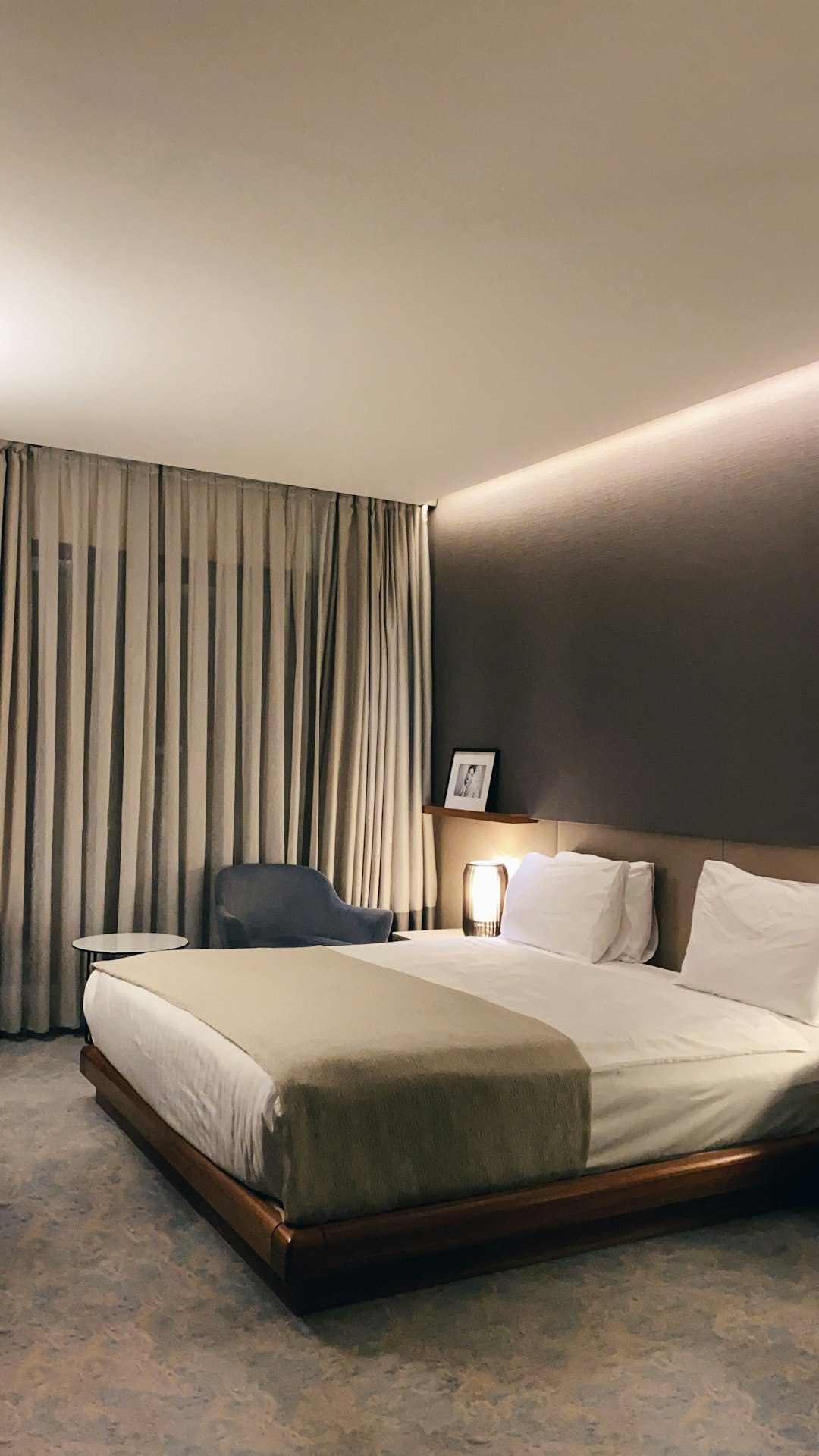 Ingerichte hotelkamer met wit bed en grijze kussens